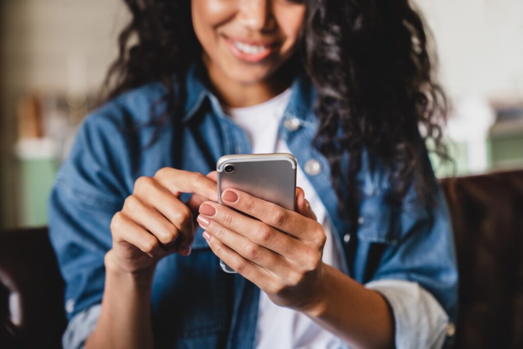 Woman smiling while looking at her cell phone.