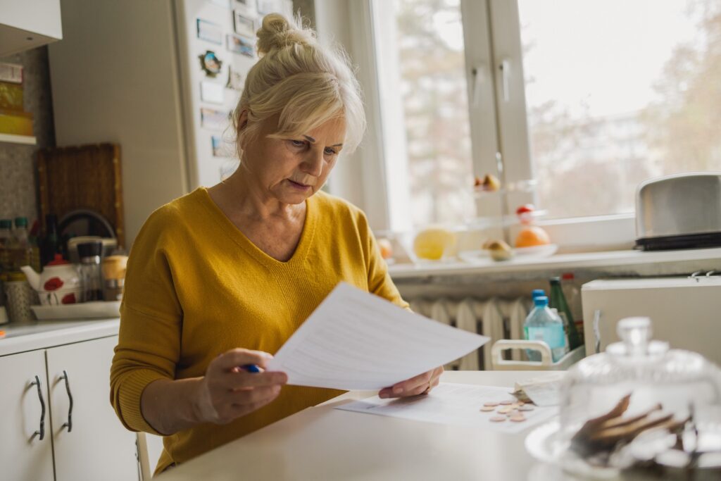 Mature woman filling out paperwork in her home.