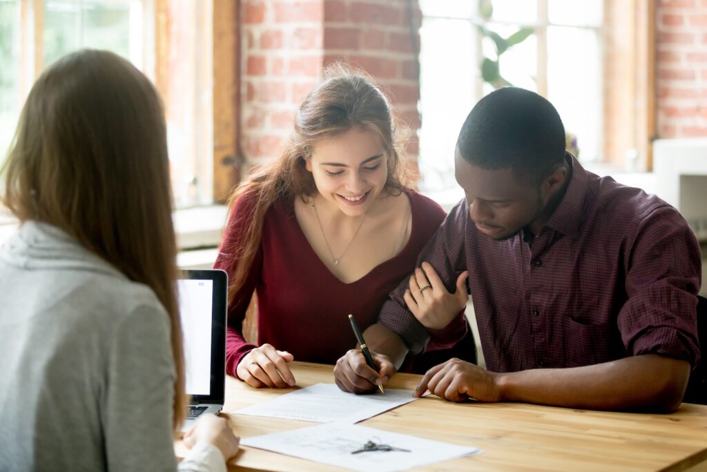 Young couple smiling while filling out paperwork.