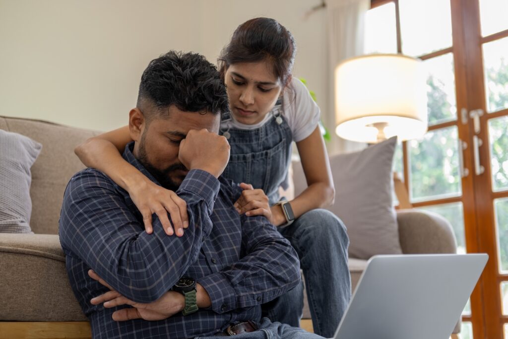 Couple sitting together looking upset.