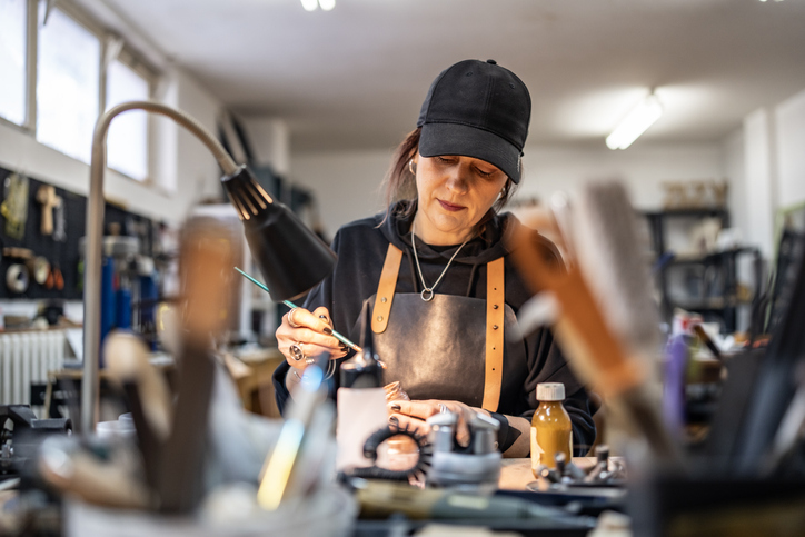 An artisan passionately creates handcrafted items with precision in a well-lit, modern workshop. The scene reflects dedication, creativity, and the essence of traditional craftsmanship blended with contemporary design.