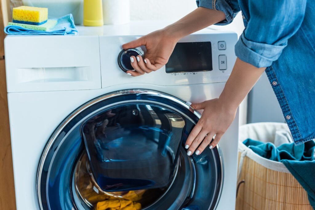 Person loading laundry into a washing machine.