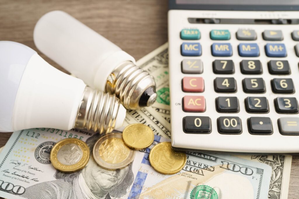 Calculator next to light bulbs, coins and money