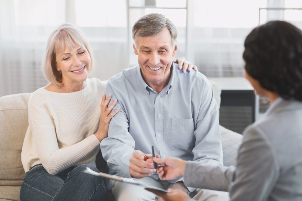 Mature couple smiling while looking over documents with an advisor.