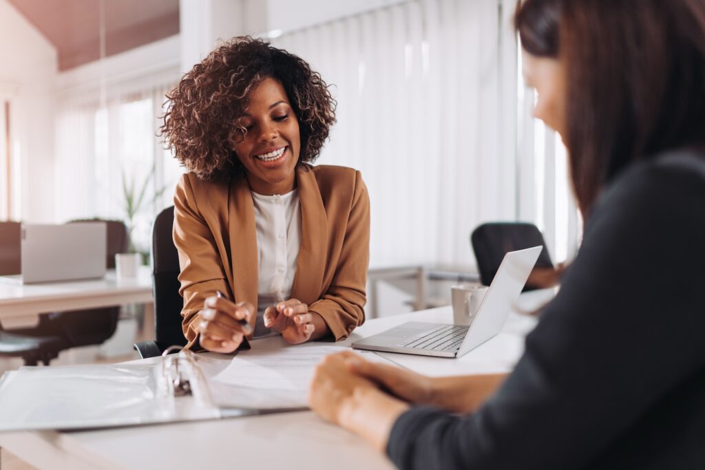 Two women smiling while looking over documents.