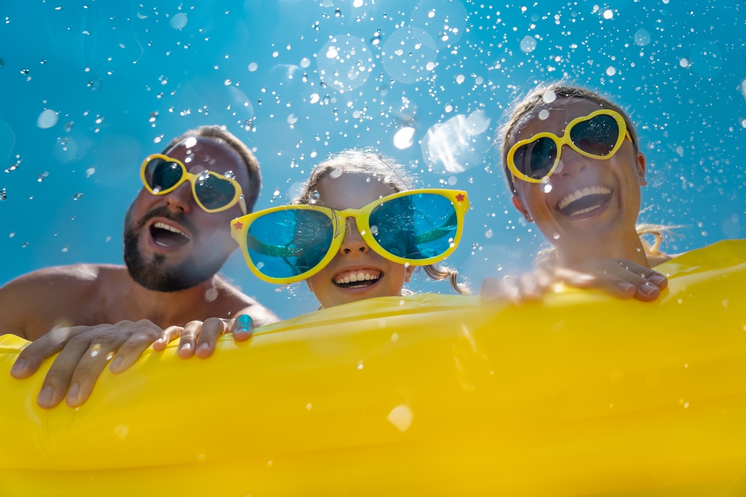 Happy family smiling on vacation while wearing sunglasses.