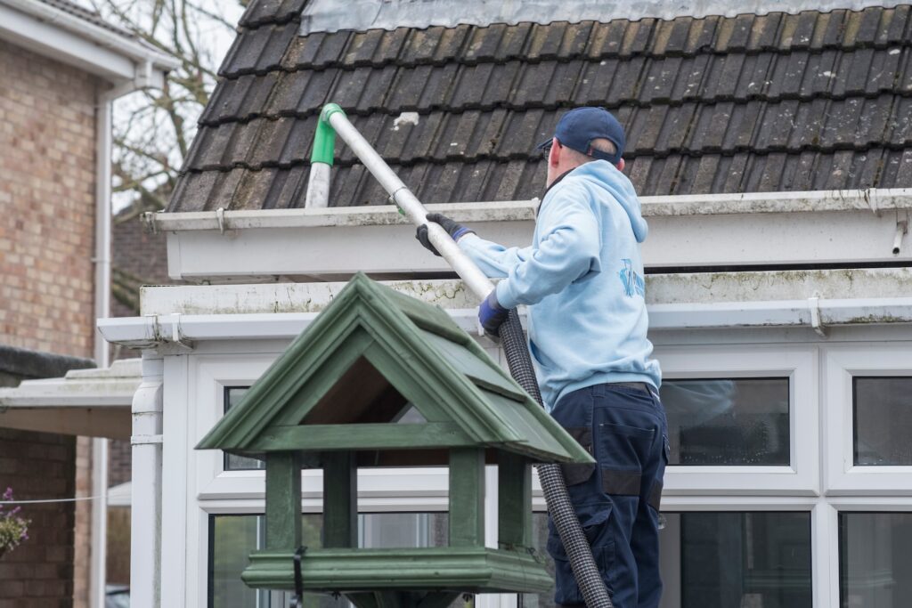 Person cleaning out gutters on a house.
