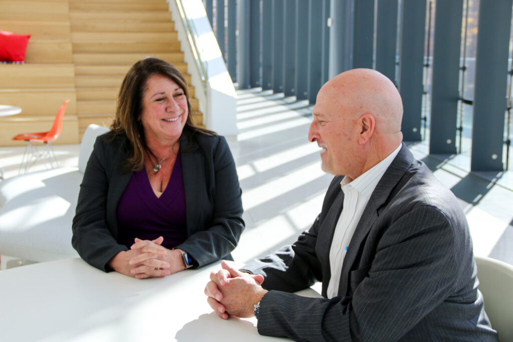 Two members of the Consumers business services team sitting together and smiling.