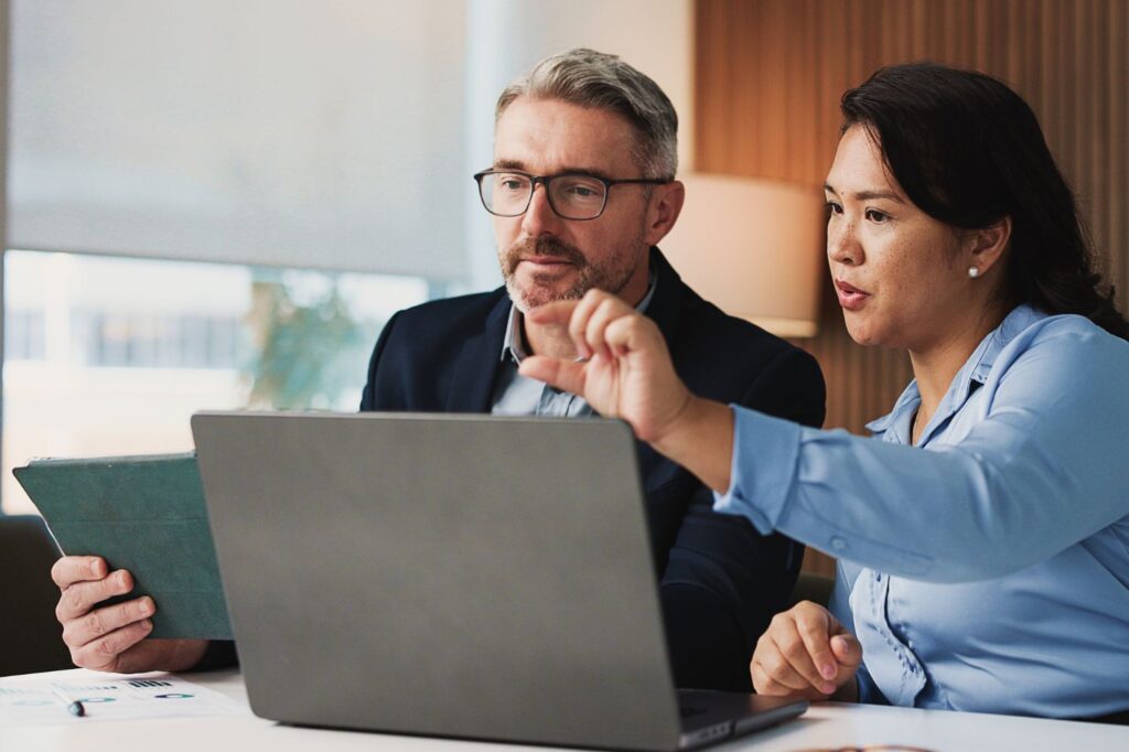 Male and female financial professionals looking over data together.