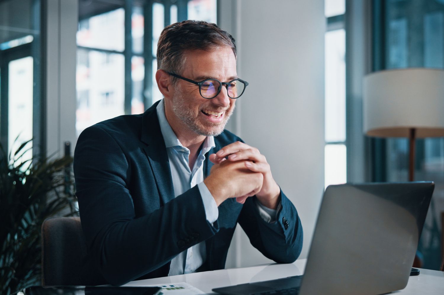 Man smiling while looking at his laptop.