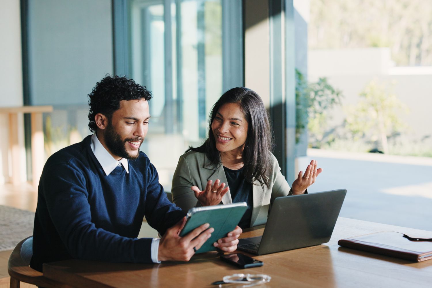 Man and woman sitting together and looking over a tablet and laptop.