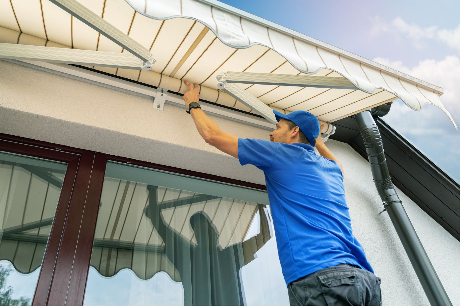 Man installing a sun shade on his house.