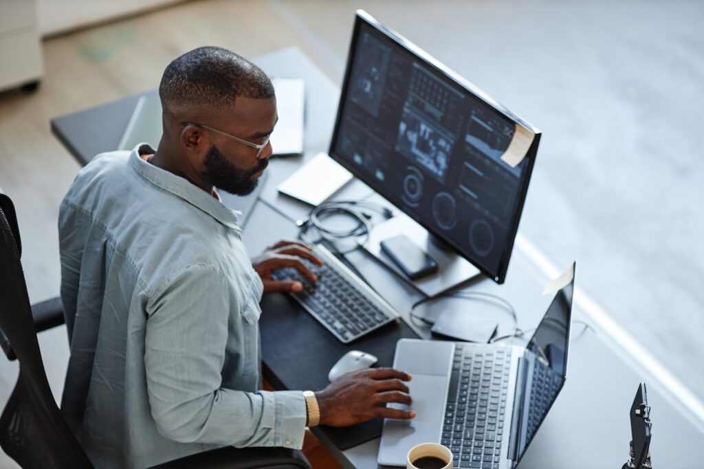 Business owner sitting at a desk and looking at computer and laptop.