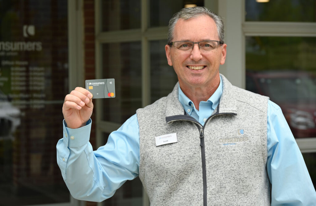 Office manager Scott Schwartzfisher holding a business credit card and smiling.