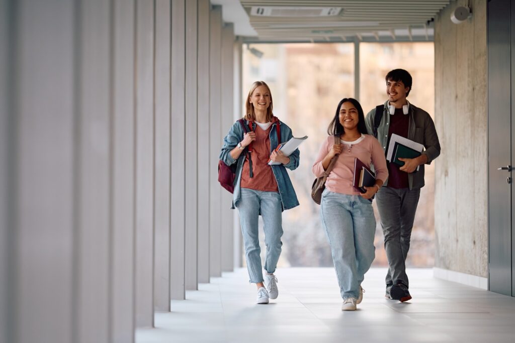 College students smiling while walking down a hallway.