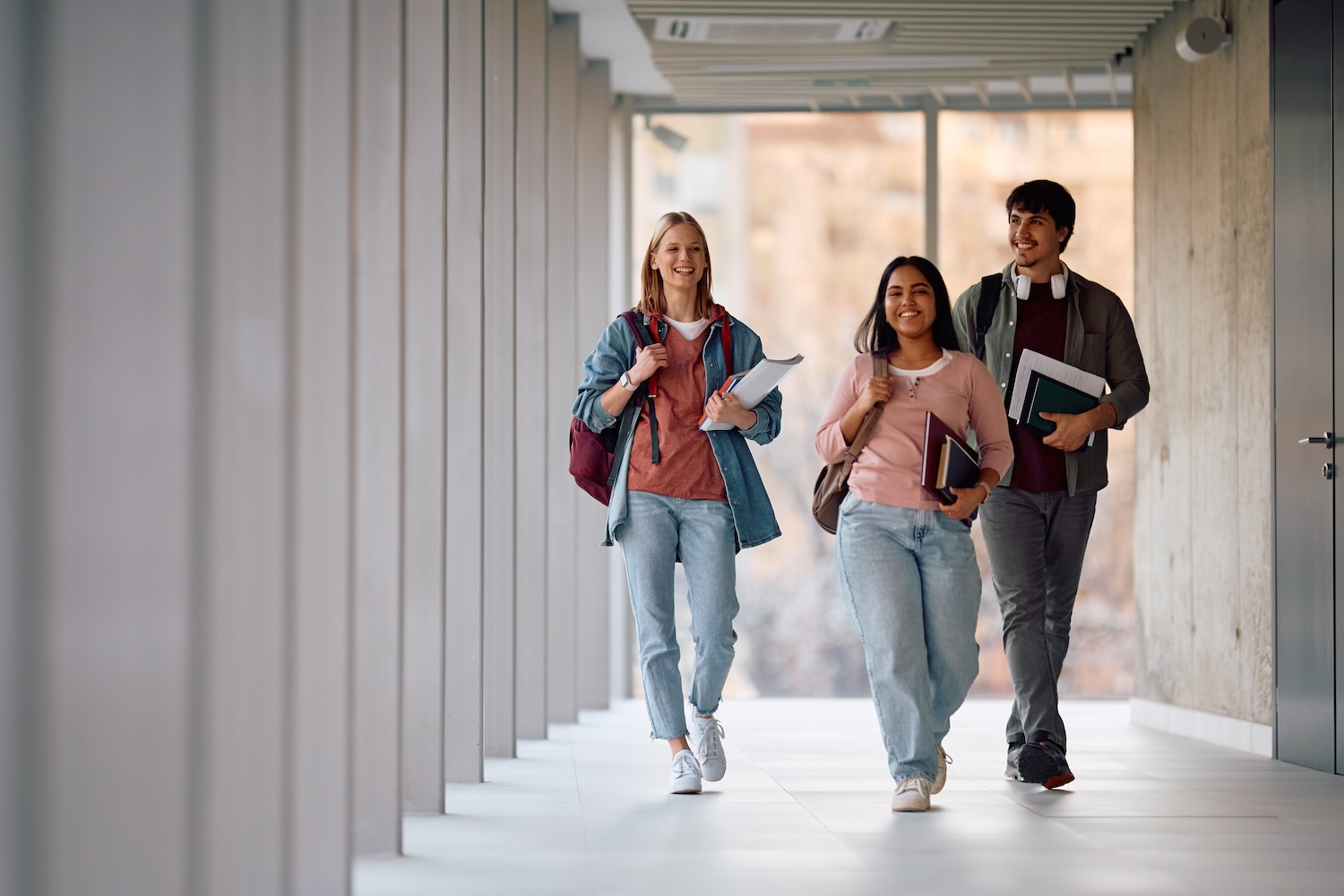 College students smiling while walking down a hallway.