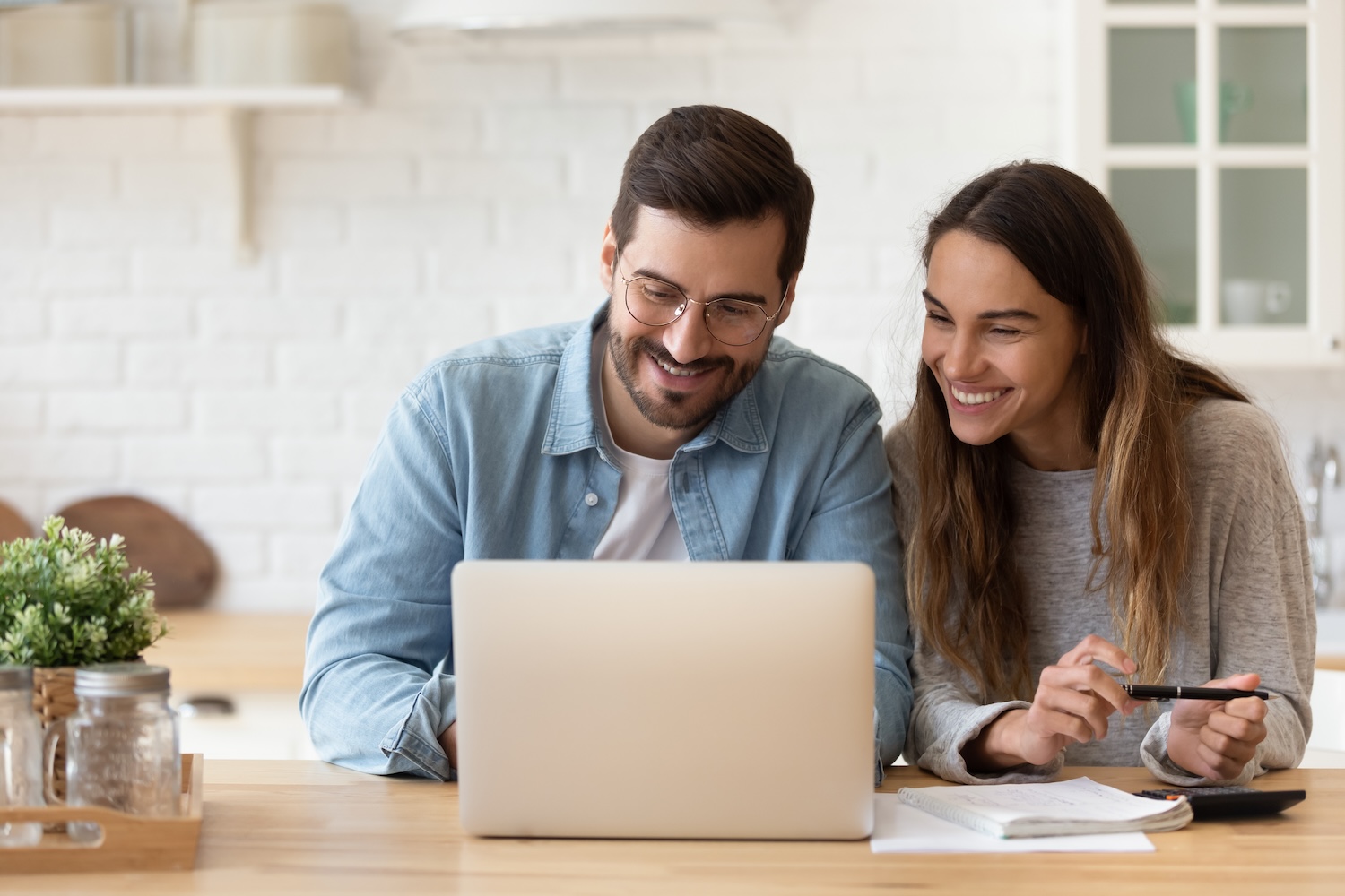 Happy young couple sitting together and looking at a laptop and paperwork.