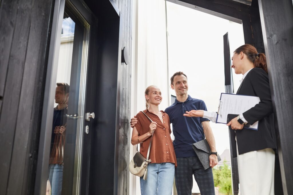 Young couple meeting with a real estate agent in front of a house.