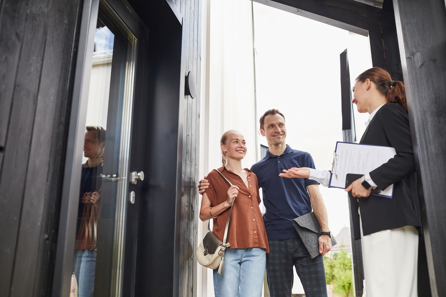 Young couple meeting with a real estate agent in front of a house.