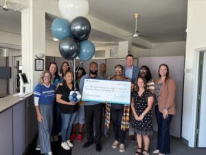 Consumers Credit Union and Neighborhoods Inc of Battle Creek (NIBC) representatives standing together and smiling and celebrating with an oversized check.