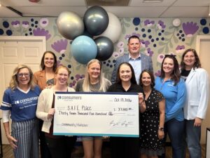 Representatives from S.A.F.E. Place and Consumers Credit Union smiling and celebrating with an oversized check.